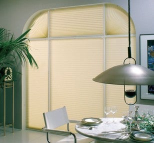 Vedere a unei sufragerii cu o fereastră mare prevăzută cu un jaluzea plisată