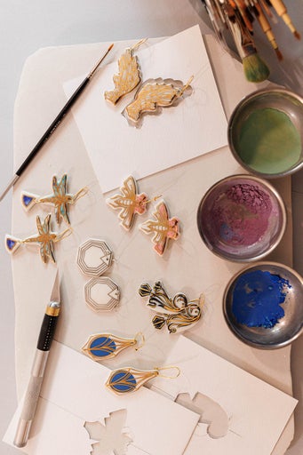 Diverse cercei cu pensule și vopsele pe o masă