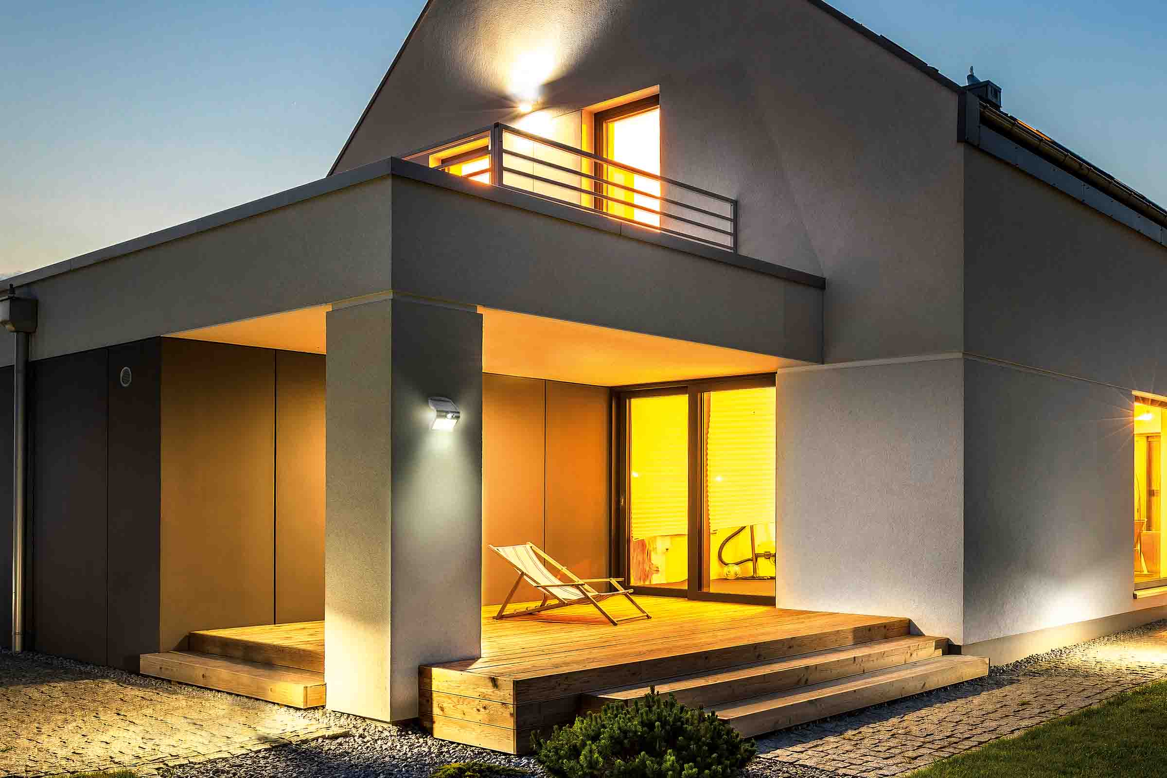 Casă modernă iluminată cu terasă din lemn și grădină