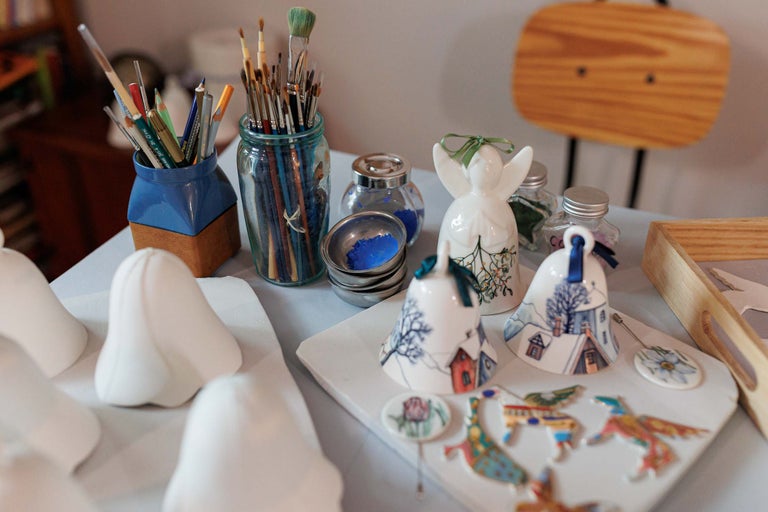 Scenă cu pensule, vopsele și clopote ceramice pictate pe o masă