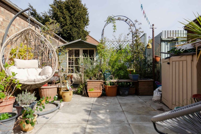 Grădină cu scaun suspendat, plante și căsuță de grădină