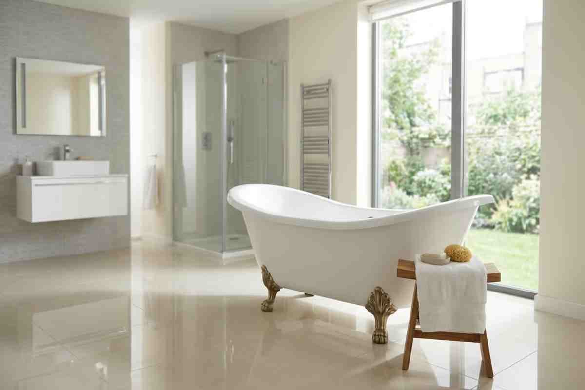 Baie luminoasă și spațioasă, cu o cadă albă de sine stătătoare pe picioare aurii, duș de tip walk-in și fereastră mare spre grădină.