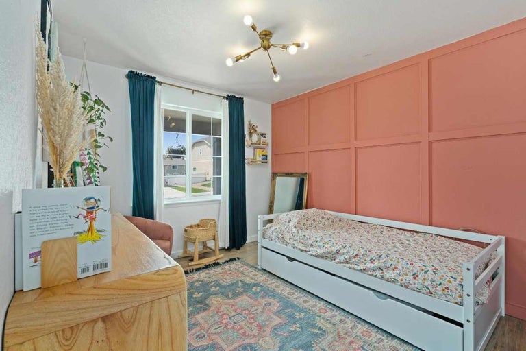 Cameră de copii cu pat, covor și perete decorativ