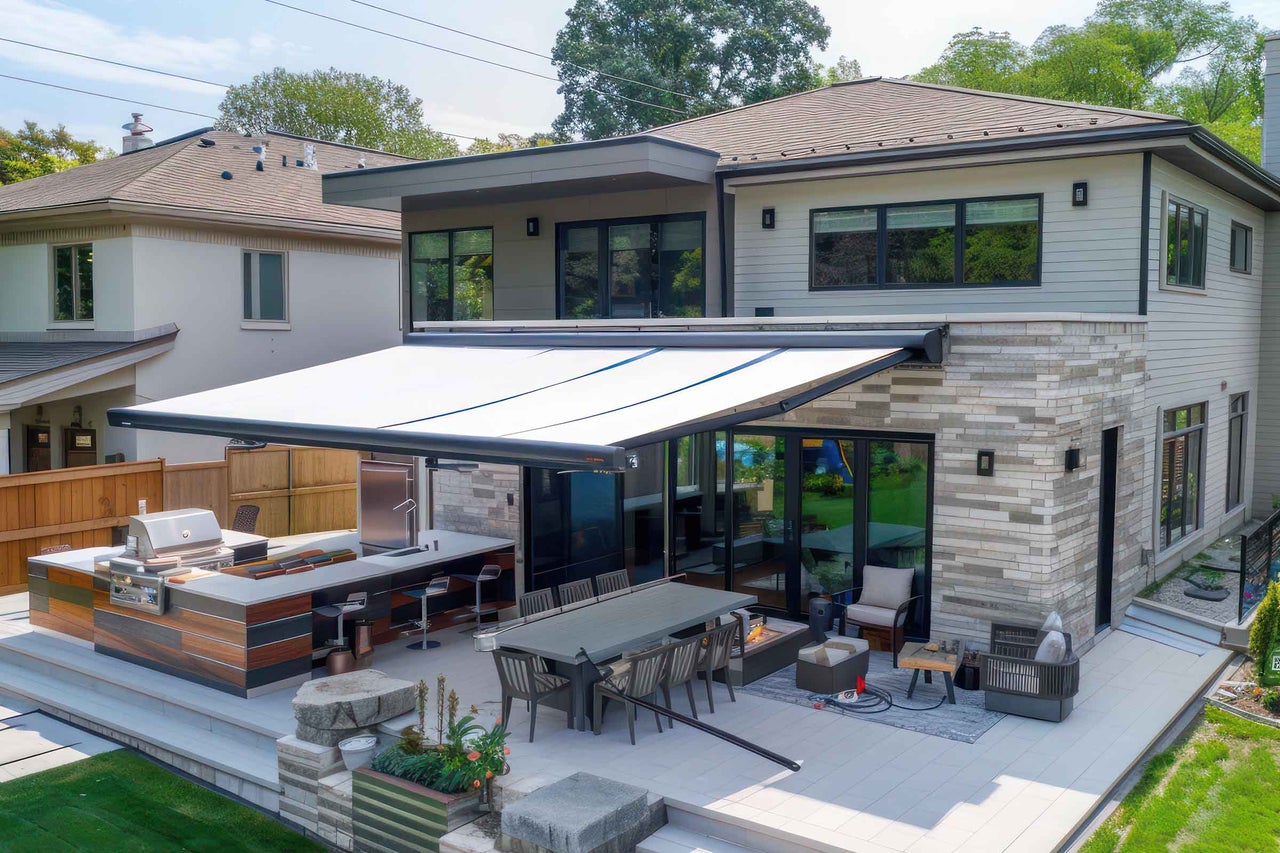 Terasa cu grătar, masă, zonă de relaxare și copertină retractabilă la o casă modernă