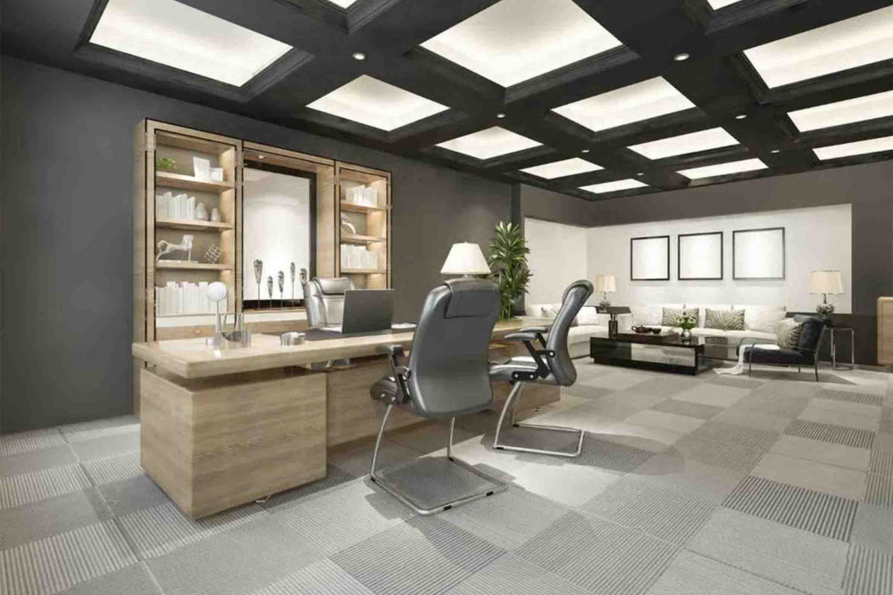 Birou modern cu birou mare din lemn, scaune de birou gri, unitate de rafturi și zonă de relaxare adiacentă cu canapea și măsuță de cafea.