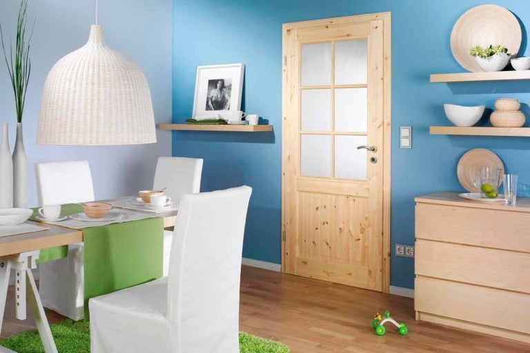 Sufragerie luminoasă cu ușă din lemn, masă și mobilier asortat.