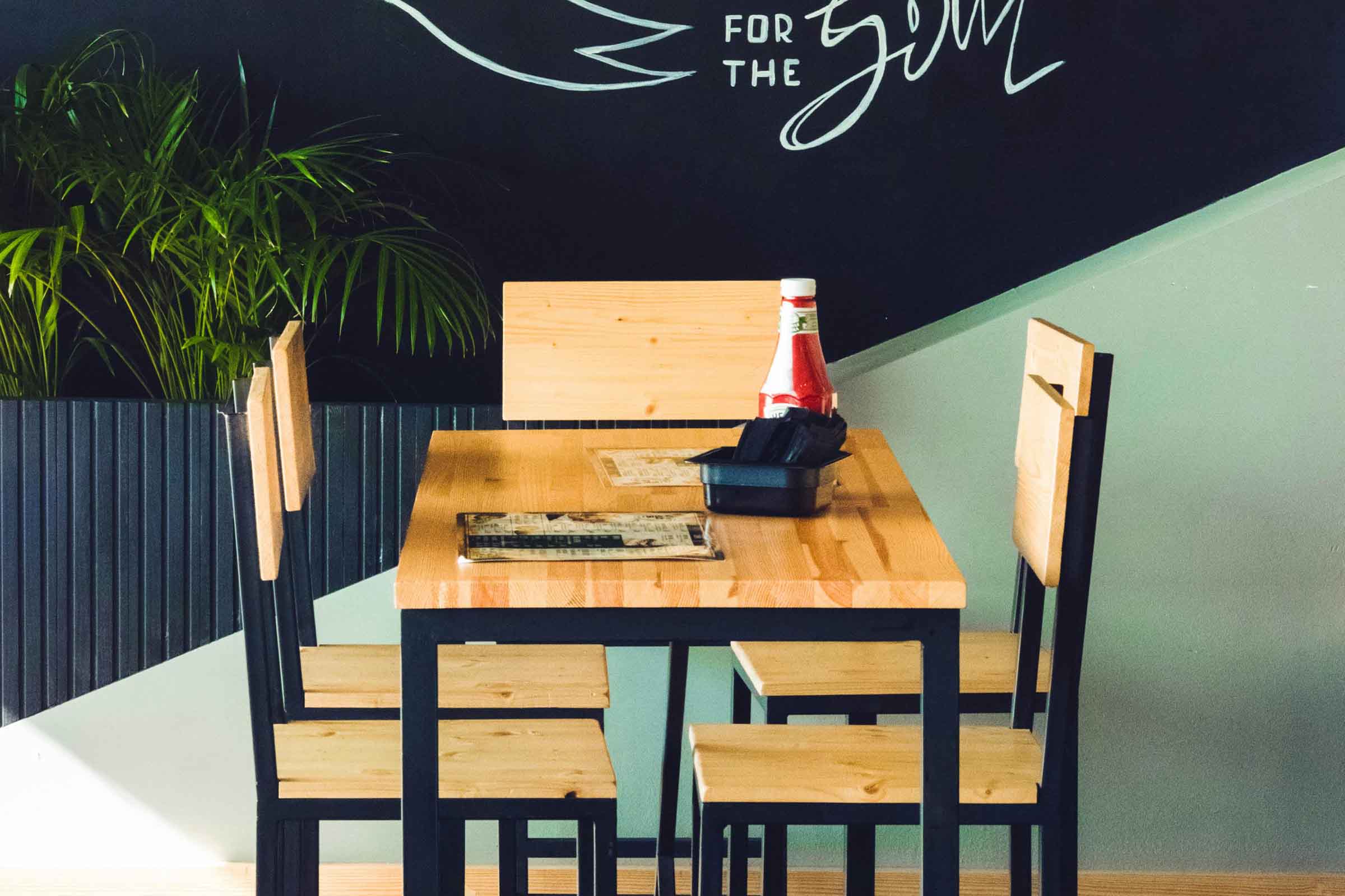Masă pătrată din lemn cu patru scaune, ideală pentru zonele de luat masa în restaurante sau cafenele.