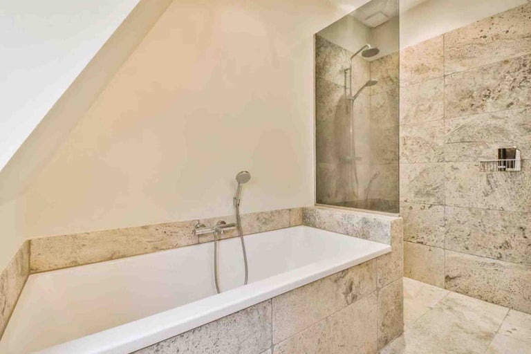 Baie modernă cu cadă încorporată și duș de tip walk-in, amenajată cu plăci ceramice cu aspect de piatră naturală.