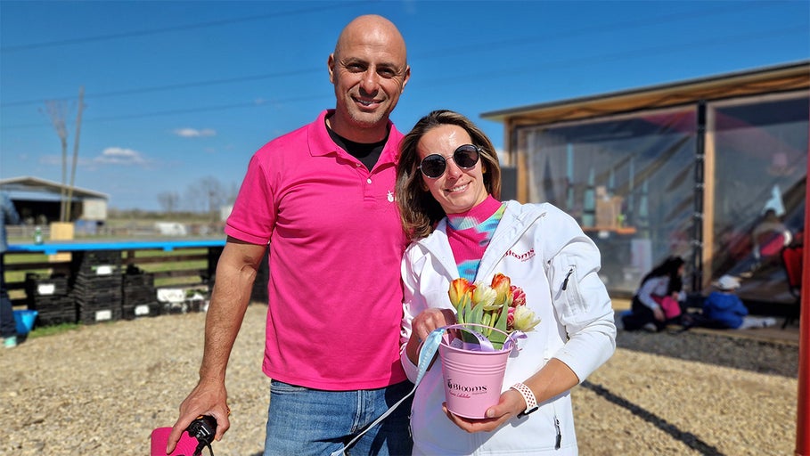 Un cuplu ține un buchet de flori într-o găleată afară.