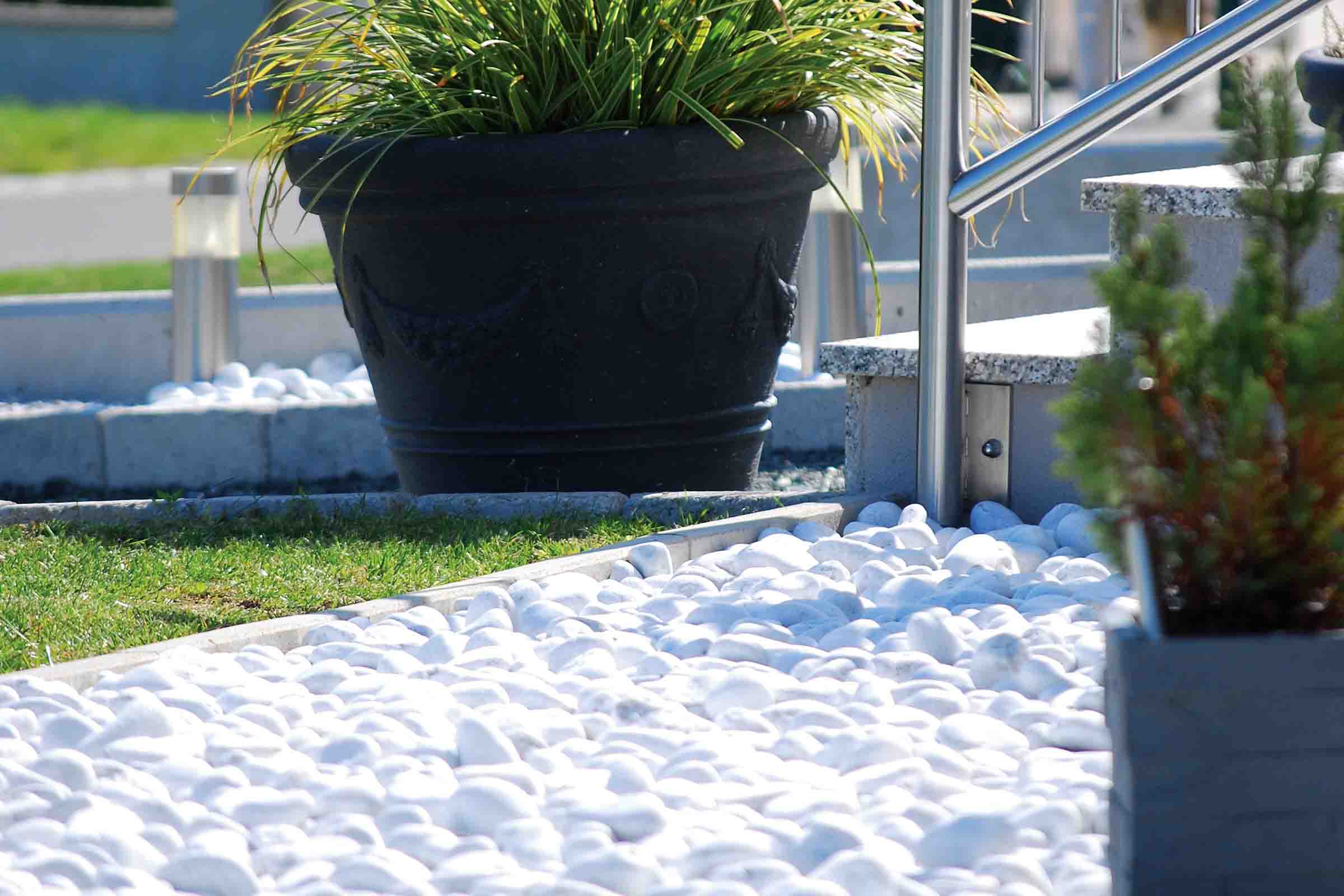 Pietre decorative albe în zona grădinii, lângă jardiniere și scări