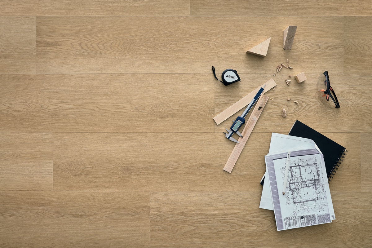 Pardoseală din vinil cu aspect de stejar montată, cu plan de construcție, șubler, ruletă și mostre de lemn.