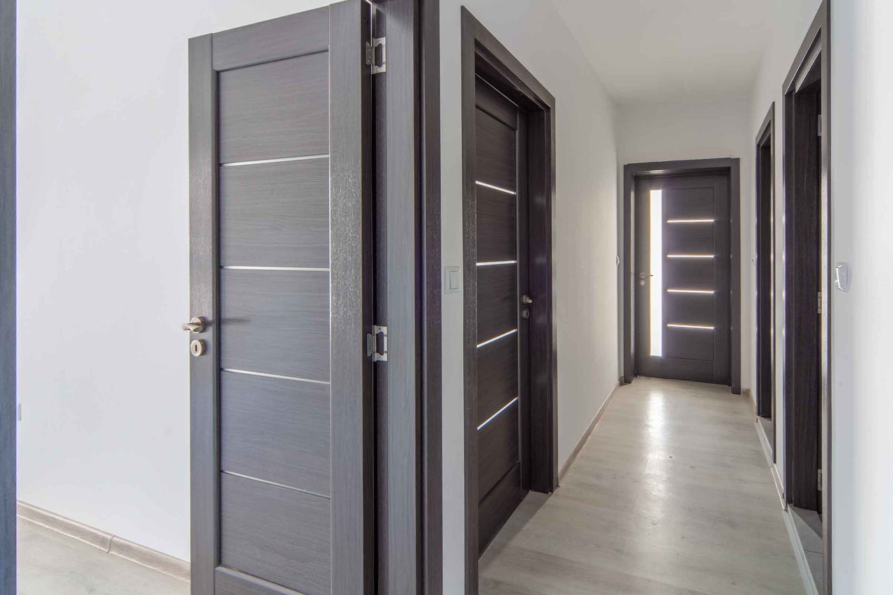 Coridor cu mai multe uși interioare din lemn cu muluri decorative orizontale