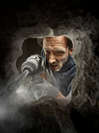 Un bărbat găurește cu un ciocan rotopercutor