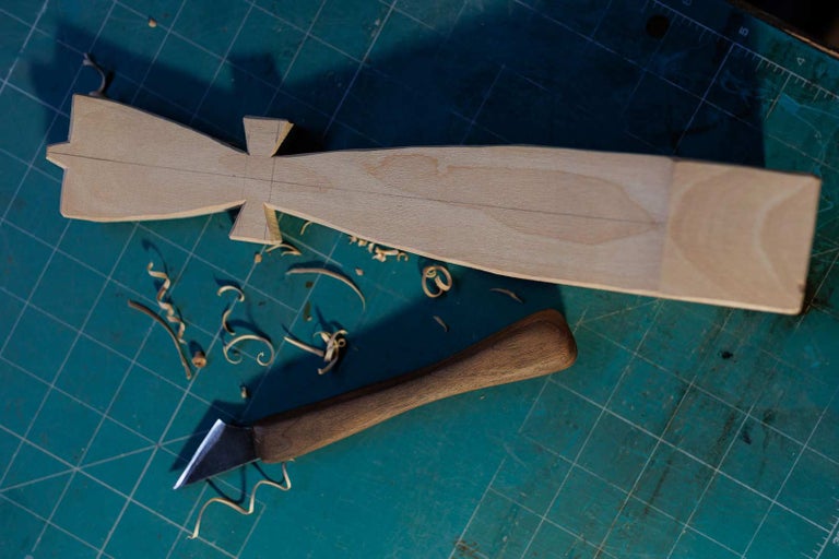 Semifabricat din lemn, cuțit de sculptură și așchii de lemn pe o placă de tăiat