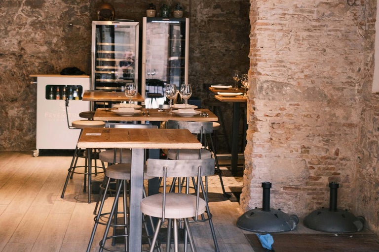 Interior cu mese din lemn, scaune de bar, frigidere pentru băuturi și pereți de piatră pentru unități de alimentație publică