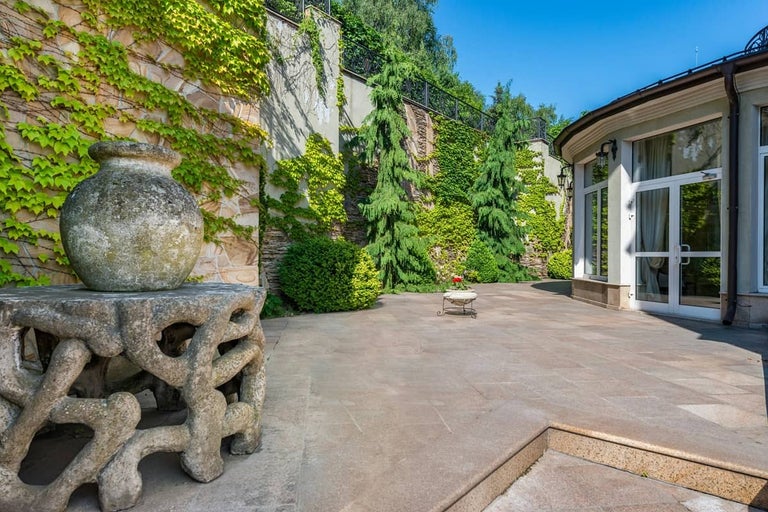 Scenă de grădină cu soclu de piatră, jardinieră și zid acoperit cu vegetație