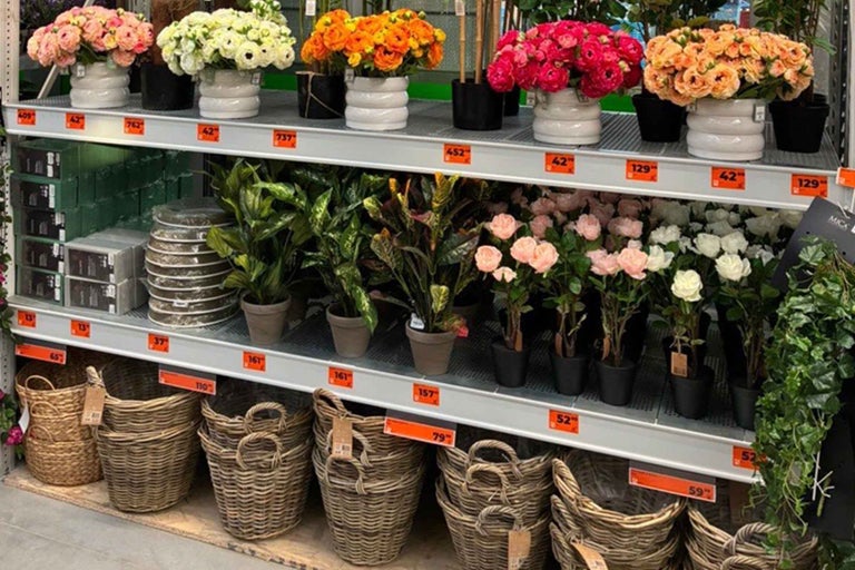 Rafturi cu flori artificiale, plante la ghiveci și coșuri în magazinul Hornbach