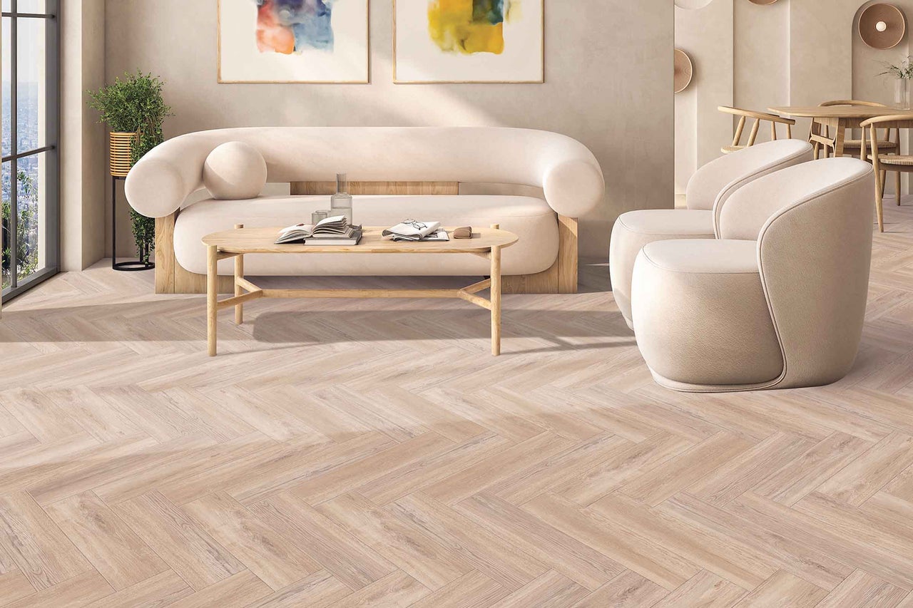 Living cu podea deschisă la culoare din lemn cu model herringbone, canapea, fotoliu și masă