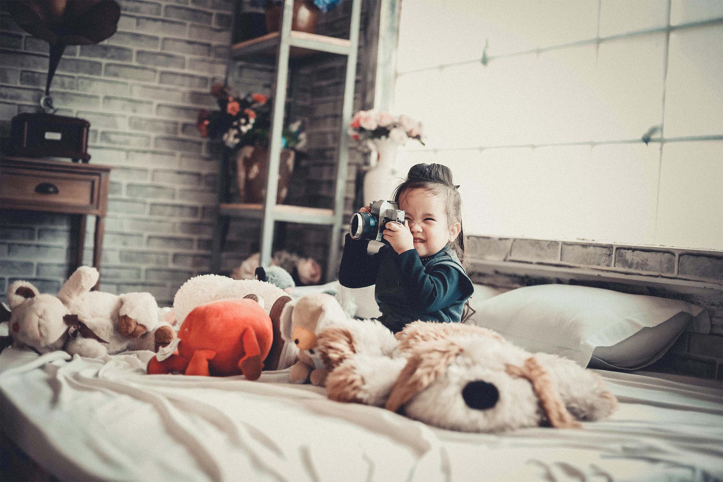 Copil fotografiază cu camera în camera copilului cu jucării