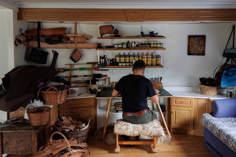 Atelier cu artizan din piele, unelte, bucăți de piele, rafturi și scaune