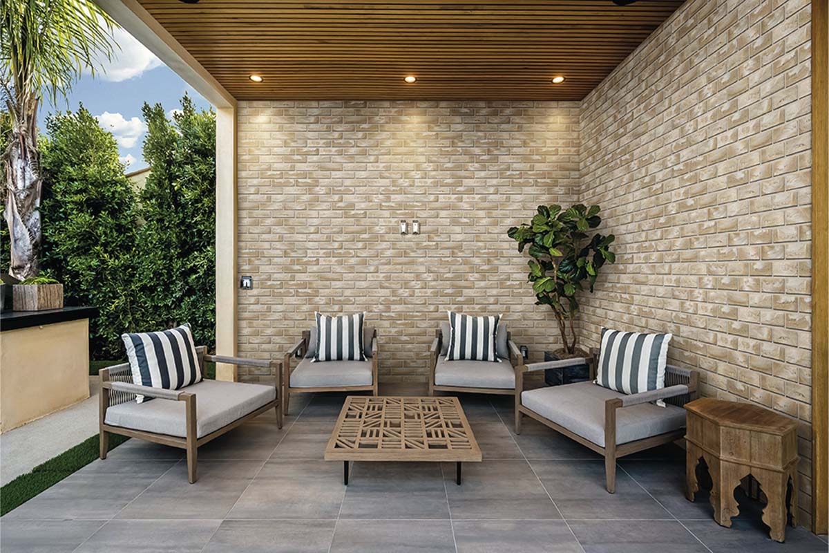 Plăcuțe de piatră cu aspect de cărămidă pe un perete exterior într-o terasă luminoasă și modernă cu mobilier de grădină și tavan din lemn.