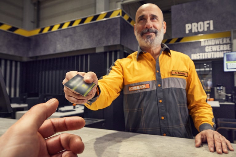 Un angajat Hornbach întinde un card de client peste un tejghea.