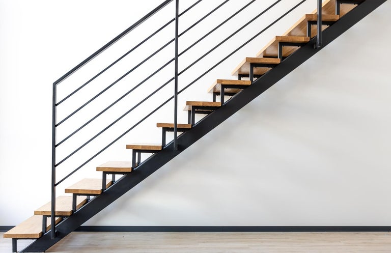 Scară interioară modernă cu trepte din lemn și balustradă din metal negru.