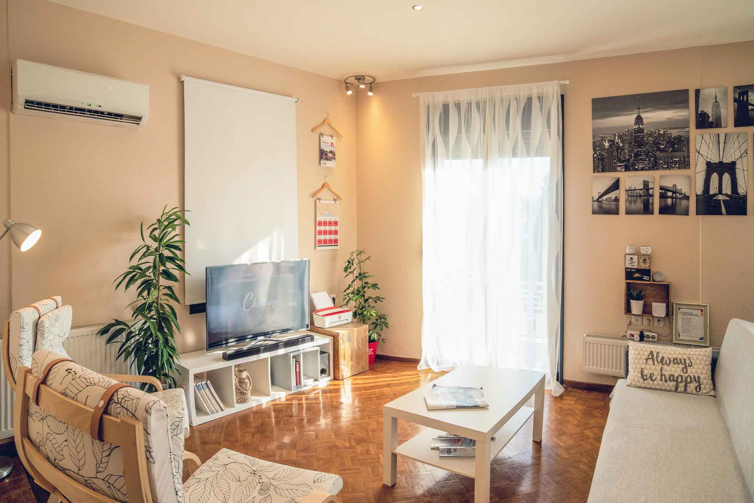 Living luminos cu televizor, canapea, fotoliu și mobilier alb