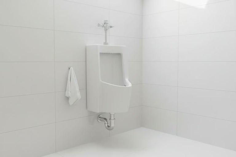 Pisoar suspendat din ceramică cu robinet de spălare și sifon într-o baie cu gresie luminoasă.