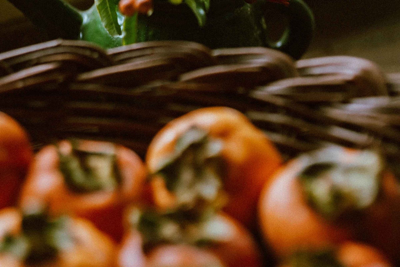 Coș cu kaki și plantă