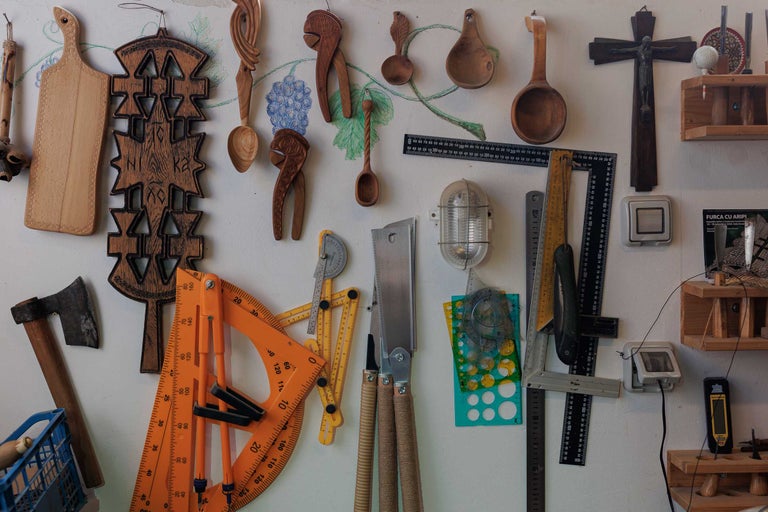 Perete cu diverse unelte și obiecte din lemn, inclusiv plăci de tăiat, linguri, spărgătoare de nuci, raportoare și fierăstraie.