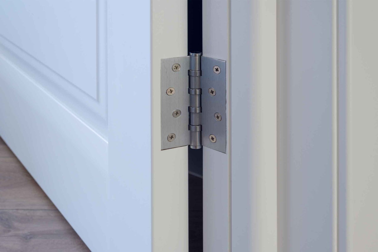 Detaliu al unei balamale de ușă pe o ușă albă