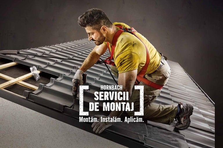 Un meșter montează țigle cu o șurubelniță cu acumulator. Serviciul de montaj Hornbach.