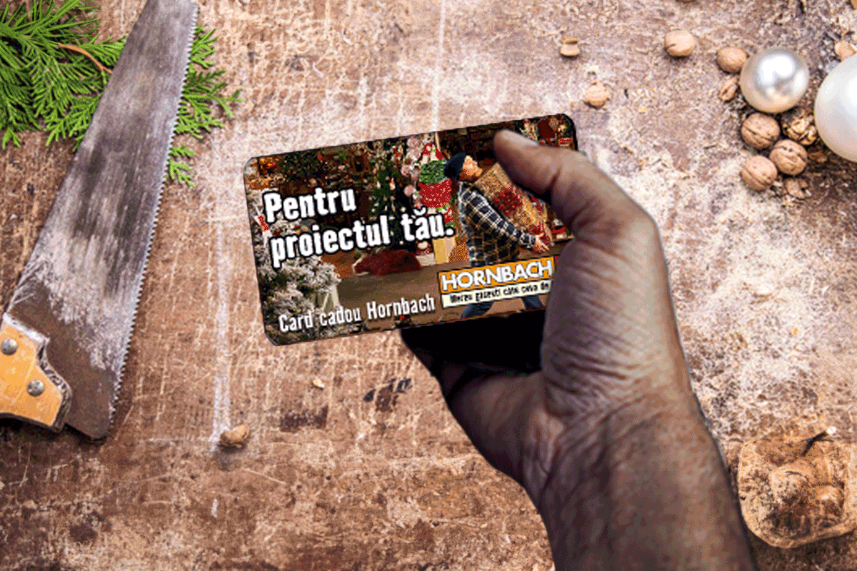 Card cadou Hornbach în mână în fața unui ferăstrău pe o masă de lemn