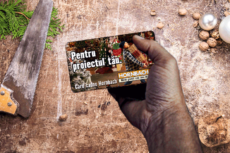 Card cadou Hornbach în mână în fața unui ferăstrău pe o masă de lemn