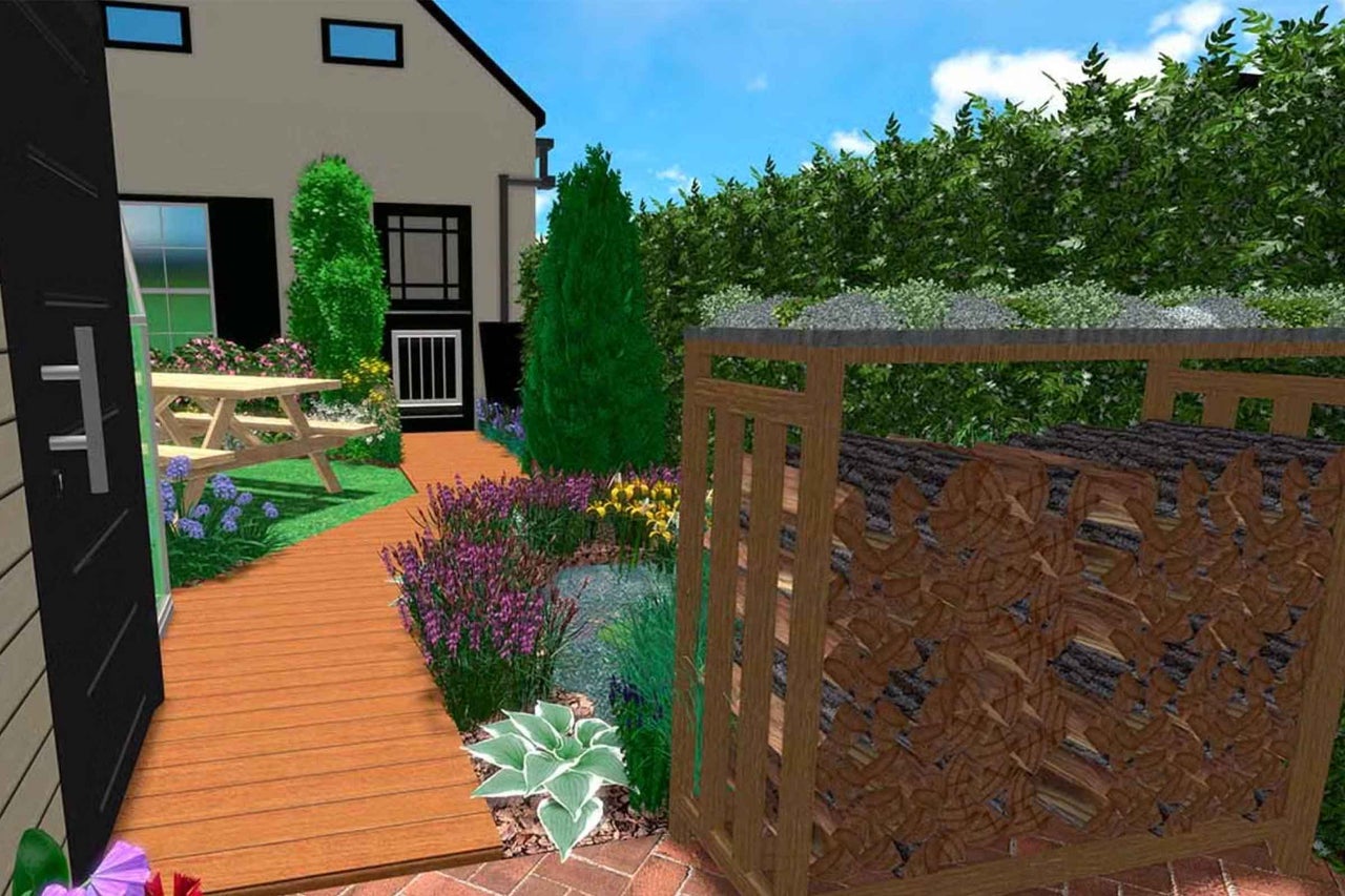 Grădină amenajată cu alee din lemn, masă de picnic, iaz, plante cu flori și un adăpost din lemn pentru lemne de foc în fața unui gard viu.