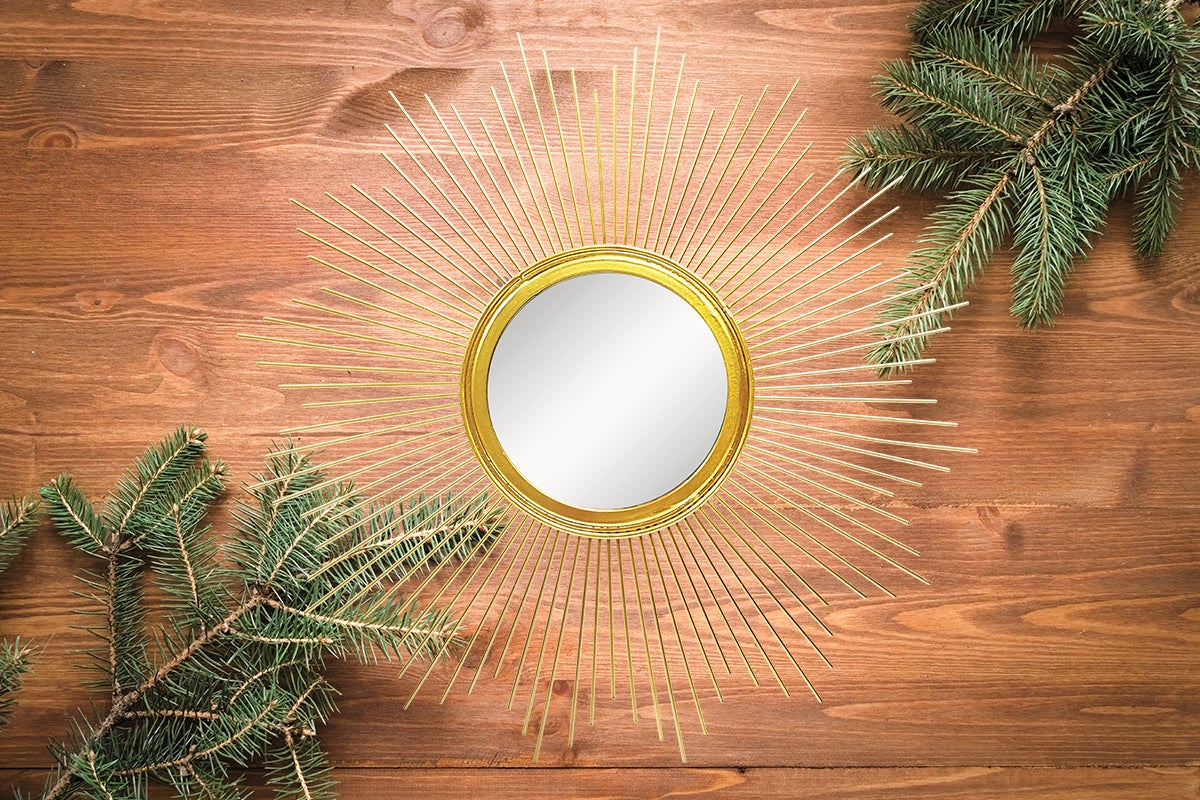 Oglindă decorativă în stil solar cu ramuri de brad pe fundal de lemn