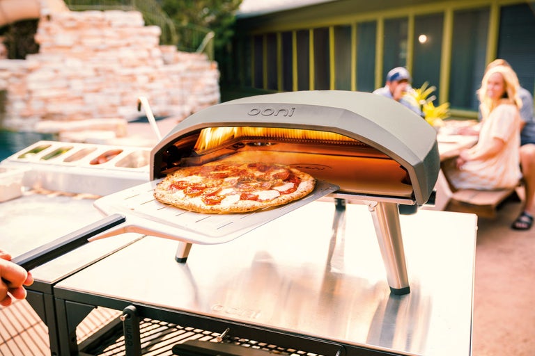 Cuptor de pizza Ooni cu pizza pe paletă de pizza în aer liber
