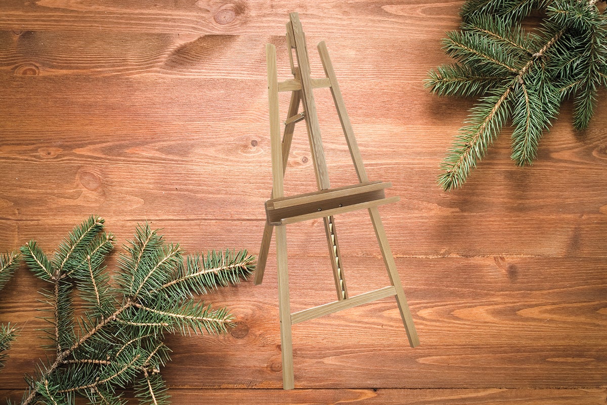 Șevalet din lemn cu ramuri de brad pe masă de lemn