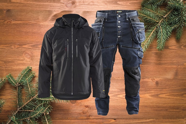 Jachetă de lucru neagră și pantaloni de lucru albaștri pe fundal de lemn