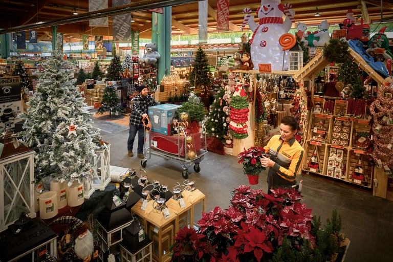 Fotografie de interior a unui magazin de bricolaj Hornbach cu decorațiuni de Crăciun și clienți la cumpărături.