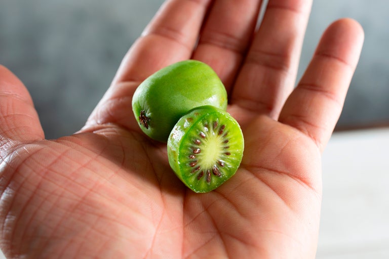 Două mini kiwi într-o palmă, una dintre ele tăiată în jumătate