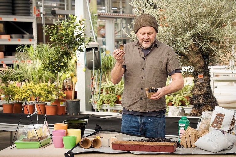 Bărbat în centrul de grădinărit cu ghivece pentru răsaduri și accesorii de grădinărit