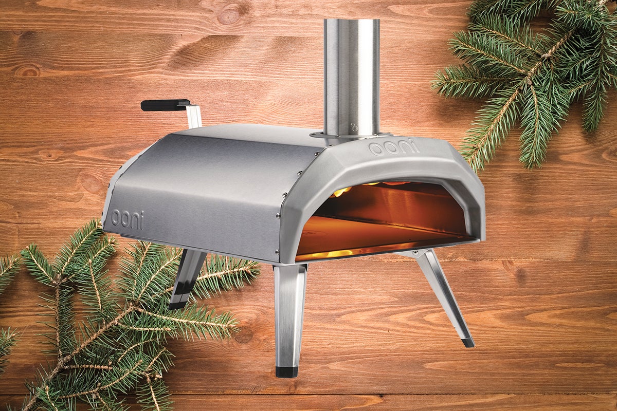Cuptor de pizza Ooni din oțel inoxidabil cu coș de fum și picioare în fața panoului de lemn