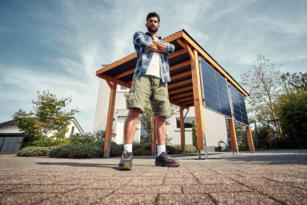 Bărbat cu brațele încrucișate în fața unui carport cu sistem solar
