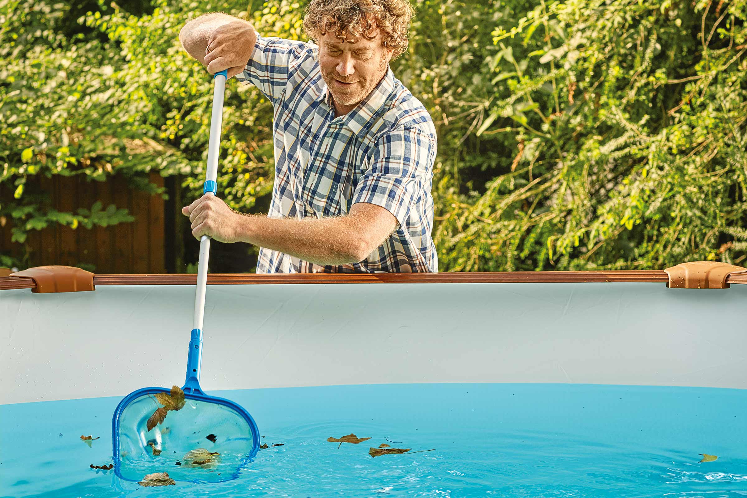 Bărbat curățând piscina de frunze cu o plasă