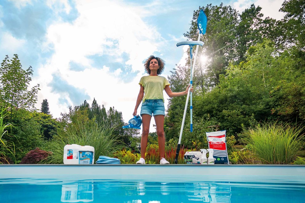 Femeie cu set de curățare piscină și substanțe chimice pentru piscină la piscină