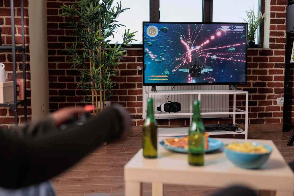 Cameră de zi cu televizor pe care rulează un joc video, masă cu gustări și băuturi
