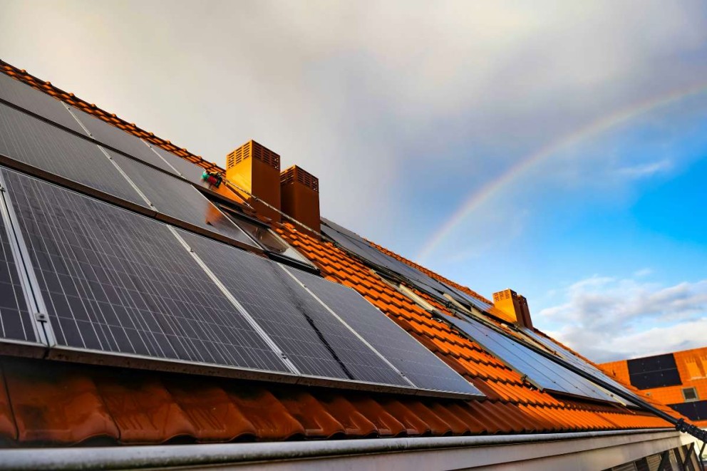 Sistem solar pe acoperișul unei case cu țigle și coșuri de fum.