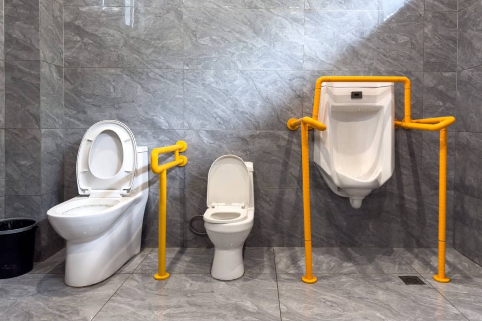 Baie accesibilă cu toalete și pisoar cu bare de sprijin